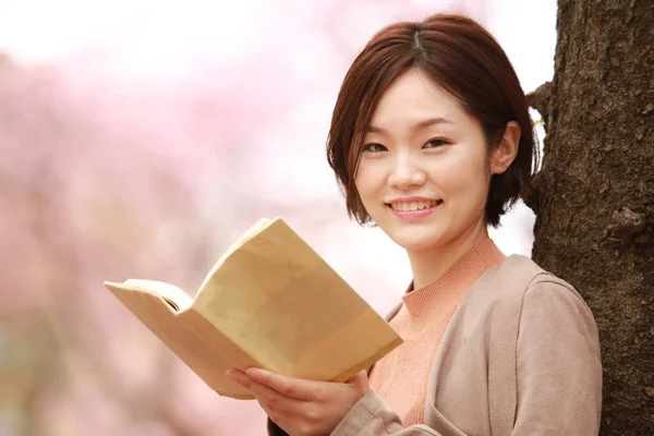 年轻的亚洲女人在公园里看书 — 图库照片