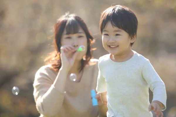 Asiatische Mutter Mit Kleinem Sohn Pustet Seifenblasen — Stockfoto