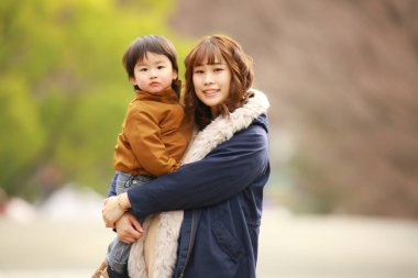Genç Asyalı anne oğluyla parkta eğleniyor.  