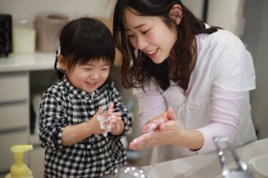 Genç Asyalı anne kızıyla el yıkıyor.