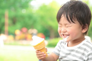 Parkta dondurma yiyen Asyalı küçük çocuk. 