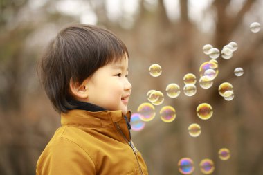 Küçük çocuk parkta sabun köpüğü üfleme