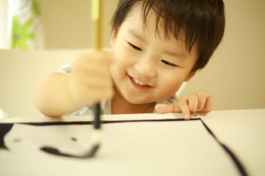 Küçük Japon çocuk fırça kaligrafi ile pratik yapıyor.