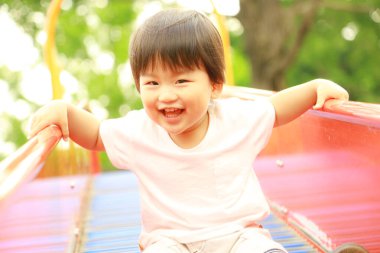 Asyalı küçük çocuk oyun alanında eğleniyor.