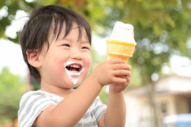 Parkta dondurma yiyen Asyalı küçük çocuk. 