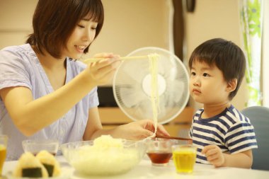 Asyalı anne ve oğlu evde yiyorlar.