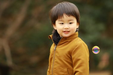 Küçük çocuk sabun köpüğüyle oynuyor.