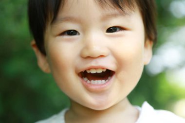 Parkta gülümseyen Asyalı küçük çocuk. 