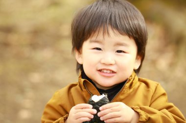 Küçük çocuk dışarıda yemek yiyor.