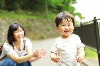Genç Asyalı anne oğluyla parkta eğleniyor.  