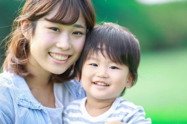 Genç Asyalı anne ve küçük oğlu parkta eğleniyorlar.  