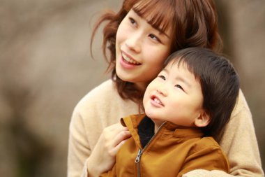 Genç Asyalı anne oğluyla parkta eğleniyor.  