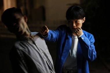 Genç Asyalı kadın sokakta bir adamla kavga ediyor. 