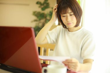 Genç Japon kadın evde çalışırken kırmızı laptop kullanıyor.