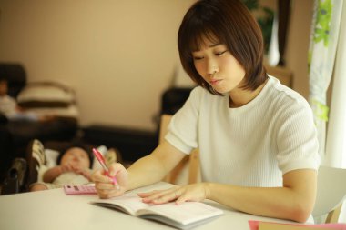 Genç Asyalı kadın evdeki deftere yazı yazıyor.