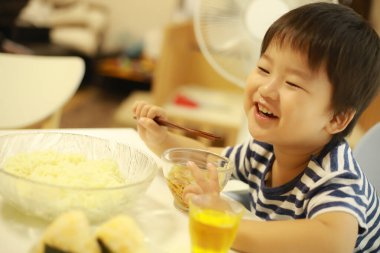 Asyalı şirin çocuk mutfakta yemek yiyor.