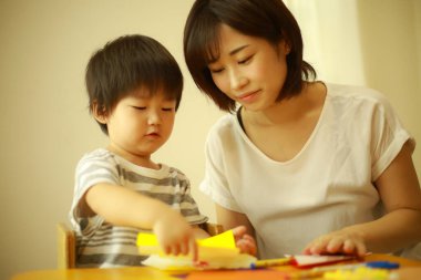 Genç Asyalı anne küçük oğluyla oynuyor.