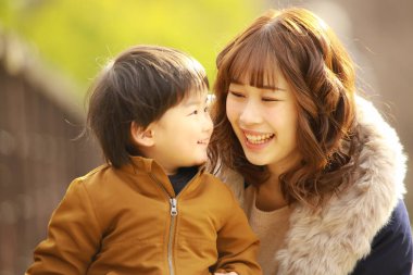 Genç Asyalı anne oğluyla parkta eğleniyor.  