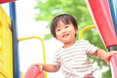 Asyalı küçük çocuk oyun alanında eğleniyor.