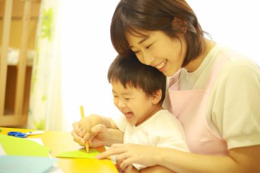 Annesiyle resim yapan küçük sevimli bir çocuk. 