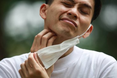 Maske takan ve kulak ağrısı çeken bir adam.