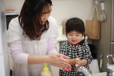 Anne kızına el yıkamayı öğretiyor.