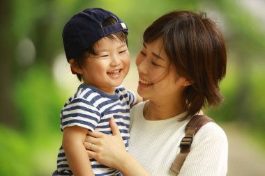 Genç anne ve sevimli küçük oğlu parkta birlikte oynuyorlar.