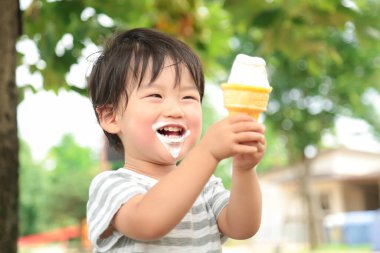 Parkta dondurma yiyen Asyalı küçük çocuk. 