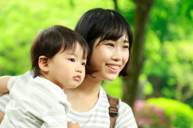 Genç Asyalı anne oğluyla parkta eğleniyor.  