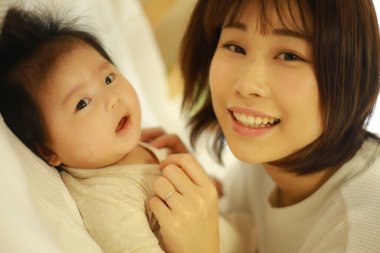 Genç Asyalı anne içeride küçük kızı oynuyor.