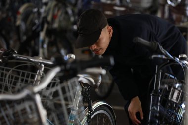 Asyalı adam sokakta bisiklet çalmaya çalıştı.