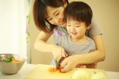 Anne ve oğul mutfakta birlikte yemek pişiriyorlar. 