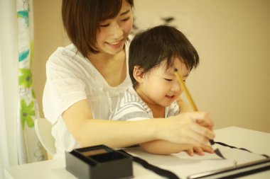 Anne ve oğul fırçayla yazı alıştırması yapıyorlar.