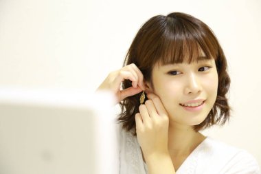 Genç Asyalı kadın aynaya makyaj yapıyor.