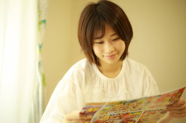 Gazete okuyan Asyalı genç bir kadının portresi