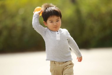 Asyalı çocuk parkta bir oyuncakla oynuyor.