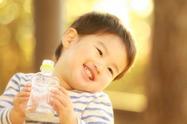 Küçük çocuk şişeden su içiyor.