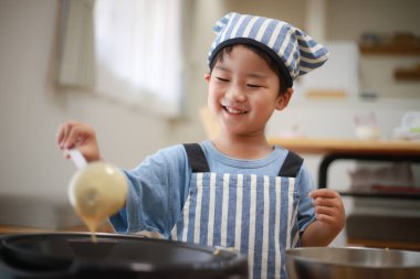Önlüklü ve şapkalı şirin bir aşçı yemek için hazırlanıyor.