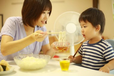 Asyalı anne ve oğlu evde yiyorlar.