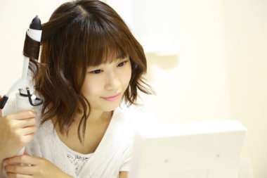 Genç Asyalı kadın aynaya makyaj yapıyor.