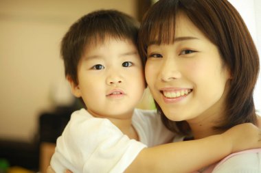 Asyalı genç kadın ve küçük oğlu sarılıyorlar. 