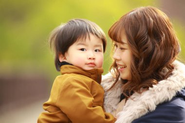 Genç Asyalı anne oğluyla parkta eğleniyor.  