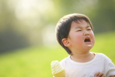 Parkta dondurma yiyen Asyalı çocuk.