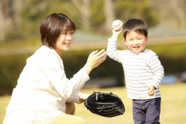 Genç anne ve sevimli küçük oğlu parkta birlikte oynuyorlar.