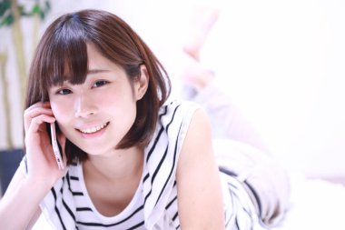 Evde akıllı telefon kullanan güzel bir Asyalı kadın.