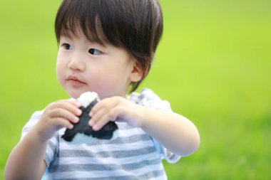 Parkta yemek yiyen Asyalı küçük çocuk. 