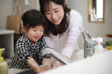 Genç Asyalı anne kızıyla el yıkıyor.