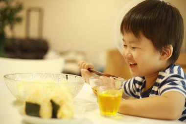 Asyalı şirin çocuk mutfakta yemek yiyor.