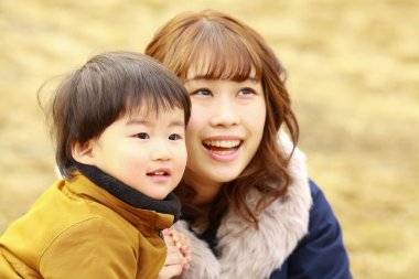 Genç Asyalı anne oğluyla parkta eğleniyor.  