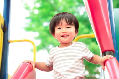 Asyalı küçük çocuk oyun alanında eğleniyor.